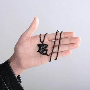 Close-up of black shark pendant necklace on palm with twisted cord chain detail