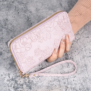 Pink faux leather long wallet with embossed floral patterns and a matching wrist strap