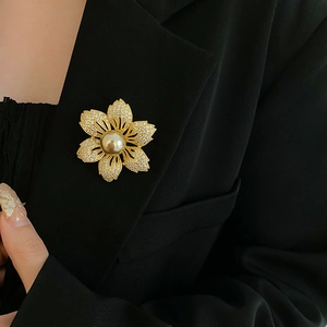 Detail of a gold flower brooch with pearls and crystals pinned to a black suit lapel