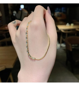 Detail of minimalist gold necklace featuring rectangular zircons and a sleek snake chain