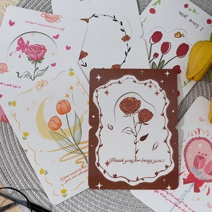 Assorted romantic floral greeting cards with English blessings on a woven mat