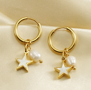 Vue macro de boucles d'oreilles étoiles et perles dorées sur satin couleur champagne