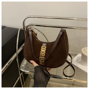 Macro detail of dark brown suede crescent bag with gold-tone COCREONE hardware logo