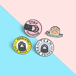 Set of four cute enamel cat paw pins featuring funny Stay Pawsitive puns for pet lovers