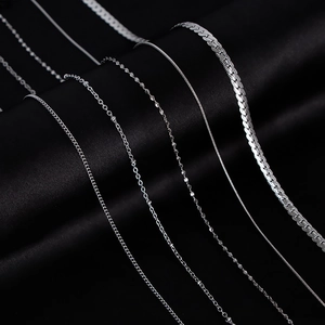Selection of silver titanium steel chains including snake and box styles on black background