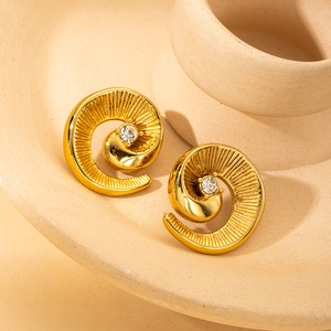 Detail of golden spiral flower earring with central crystal and radial texture