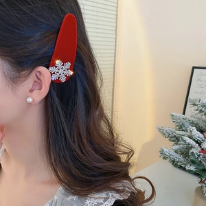Close-up of red velvet hair clip with sparkling rhinestone snowflake detail on model