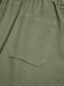 Macro shot of olive green linen trousers showing the durable back pocket stitching and texture