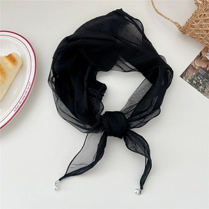 Detail of black lace neck scarf with pearl charms and silver metal buckles on white background
