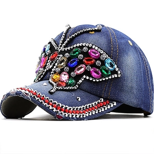 Detail view of denim baseball cap with large butterfly rhinestone and jewel embellishments