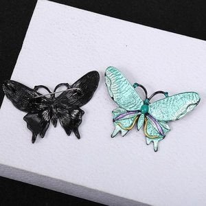 Macro shot of butterfly brooch featuring green enamel wings and a secure pin clasp