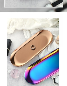 Detail of rose gold and rainbow stainless steel oval trays on a textured surface
