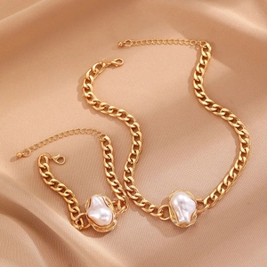 Gold Cuban chain necklace and bracelet set featuring baroque pearls on beige silk