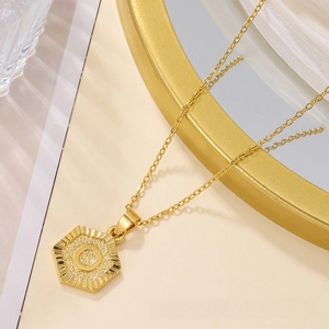 Detail of a golden hexagonal pendant with sunburst texture on a delicate chain