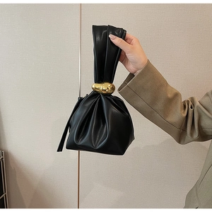 Detailed view of black pleated dumpling bag with unique irregular gold metal buckle