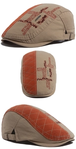 Detail view of khaki retro newsboy cap showing orange quilted panels and embroidery