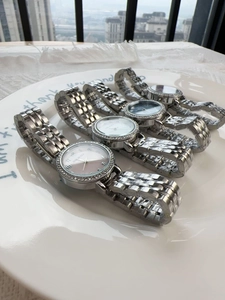 Detail of luxury silver women's watches with diamond bezels on a white ceramic tray