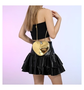 Detail einer herzförmigen goldenen Tasche im Y2K-Stil getragen an der Schulter