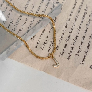 Détail macro du pendentif lettre J doré avec zircons sur une chaîne torsadée