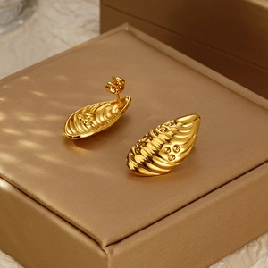 Irregular golden shell earrings with 18K gold plating on textured gift box background
