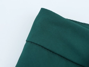 Macro shot of dark green suit trousers fabric showing fine texture and neat stitching details