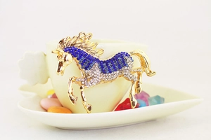 Detailed macro view of a gold-toned horse keychain encrusted with blue and white rhinestones