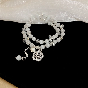 Detail of double-layer white beaded bracelet with silver rose pendant on black velvet