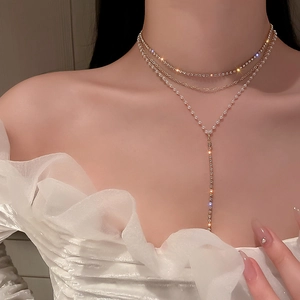 Close-up of multilayered gold-tone necklace with pearls and rhinestone Y-shaped pendant