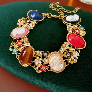 Macro detail of vintage gold bracelet with colorful gems and cameo on green velvet
