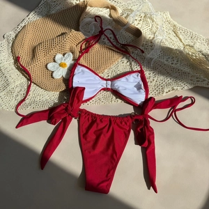Flat lay of red bikini set with shell details and bow ties on summer vacation background