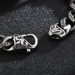 Macro shot of gothic-style engraved links and lobster clasp on silver stainless steel bracelet