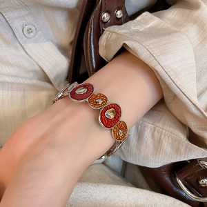 Detail shot of chunky silver chain bracelet with red and orange enamel on model's wrist