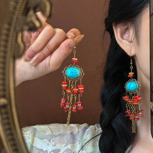 Detailed close-up of vintage bronze flower earrings with turquoise beads and tassels