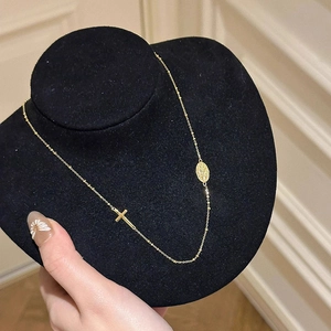 Collier doré avec pendentif croix et médaille ovale sur un support en velours noir