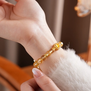Gros plan d'un bracelet en perles de citrine jaune avec breloques cœur dorées au poignet