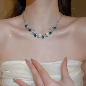 Detail of silver floral necklace set with green zircon stones on model's neck