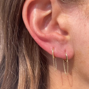 Close-up of gold S925 silver hoop earrings with dangling chains on a model ear