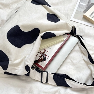 Corduroy cow print crossbody bag showing large capacity with laptop and books