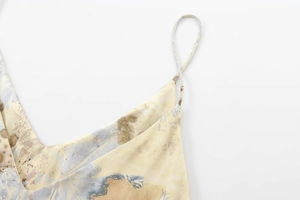 Détail du décolleté en V et des fines bretelles d'une robe longue en satin imprimé