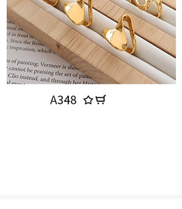Close-up of gold shell stud earrings on a wooden jewelry tray with a vintage book