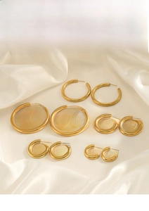 Macro shot of gold hoop earrings set in various sizes displayed on elegant cream silk fabric