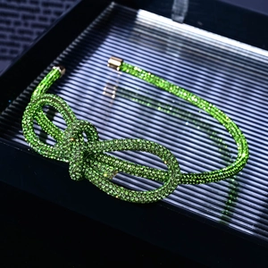 Close-up of a sparkling green rhinestone bow necklace displayed in a dark gift box