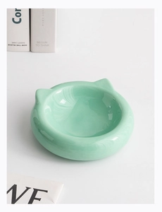 Detailed view of mint green cat ear ceramic bowl on minimalist background with natural lighting