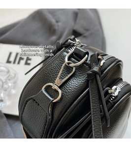 Close-up of premium silver-tone hardware and litchi grain texture on black crossbody bag