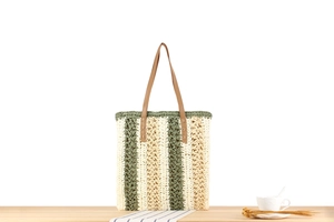 Detail of green striped paper rope woven tote bag with brown leather handles