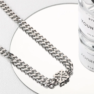 Polished titanium steel Cuban link necklace with cross pendant on a reflective surface
