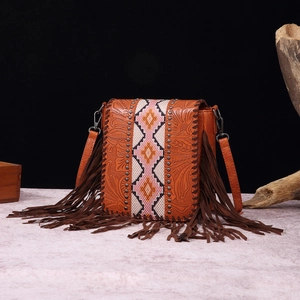 Detail view of Bohemian leather bag with floral embossing, metal rivets, and long side fringes