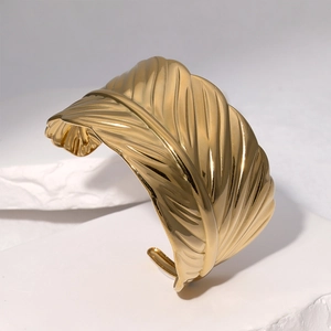 Polished 18k gold stainless steel leaf feather open bangle bracelet on white stone base