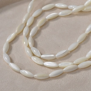 Detailed view of natural oval white shell beads on a soft beige fabric background