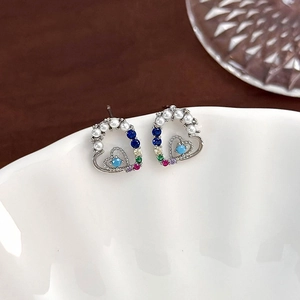 Detail of heart-shaped stud earrings featuring colorful zircons and pearl accents